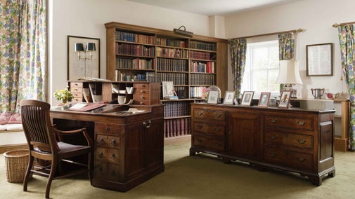 An image of the Library at Greys Court, Oxfordshire with large wooden bookcase, wooden cabinet and imposing wooden desk in the centre of the room